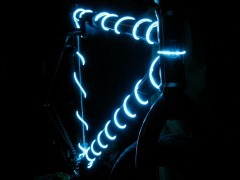 A dark bike is illuminated by christmas tree style lights