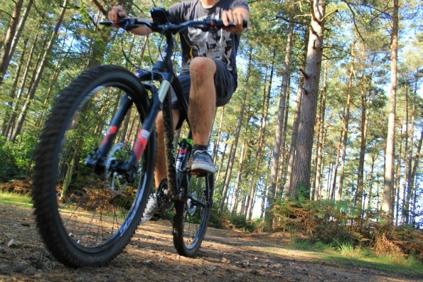 Ground up view of the Voodoo Canzo with front wheel in slight blur showing the speed and mud on the rider