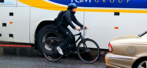 Cyclist pedalling next to a bus on London Bridge